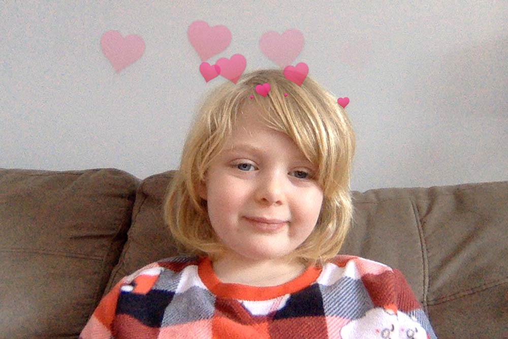 A photo of a girl smiling, with read hearts above her head.